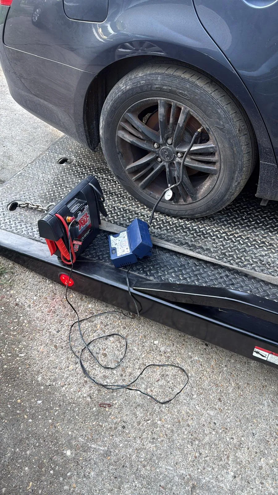 Roadside tire inflation equipment beside a vehicle on a tow truck